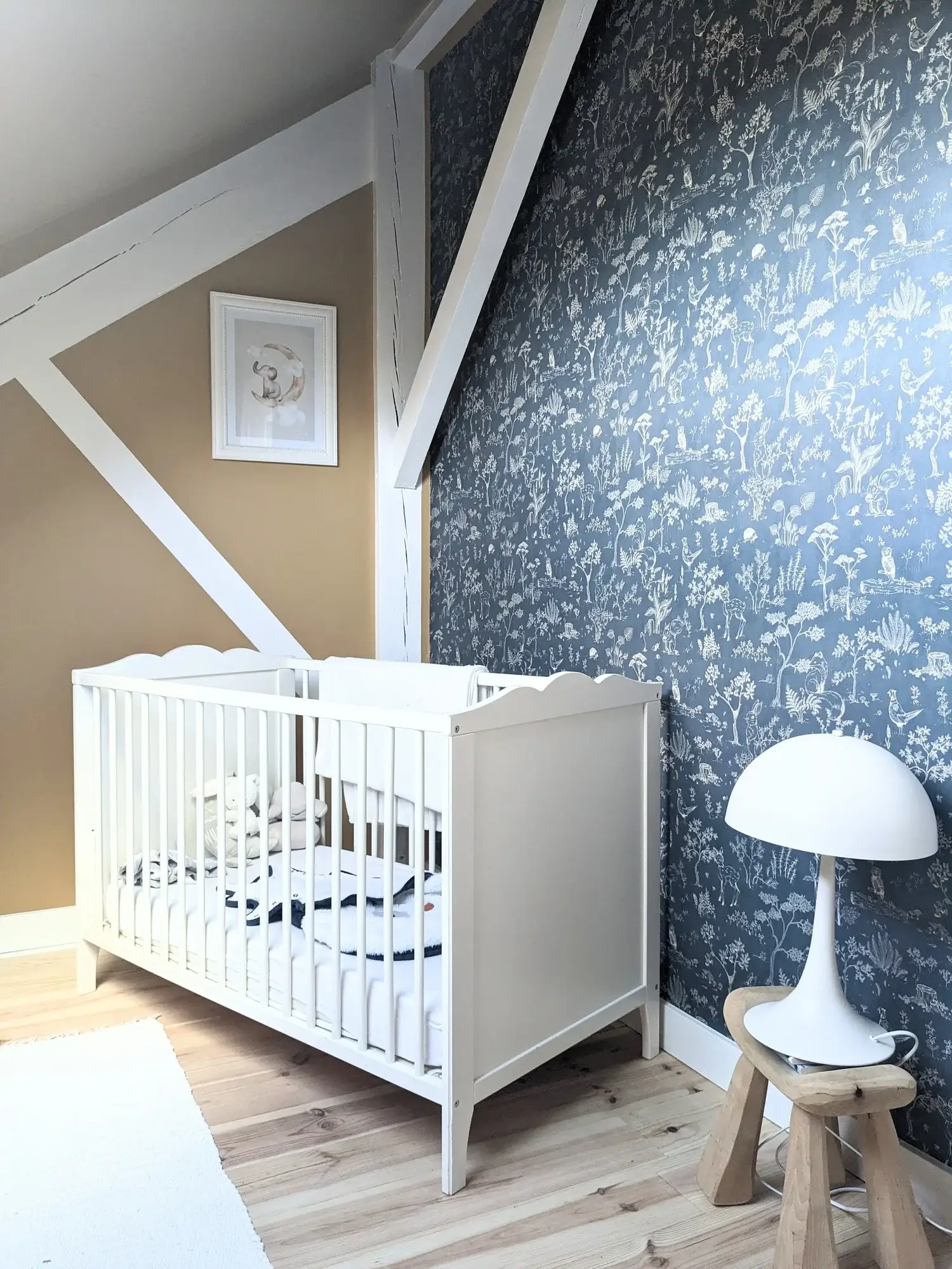 Chambre de bébé sous comble, lit à barreaux blanc et papier peint bleu nuit