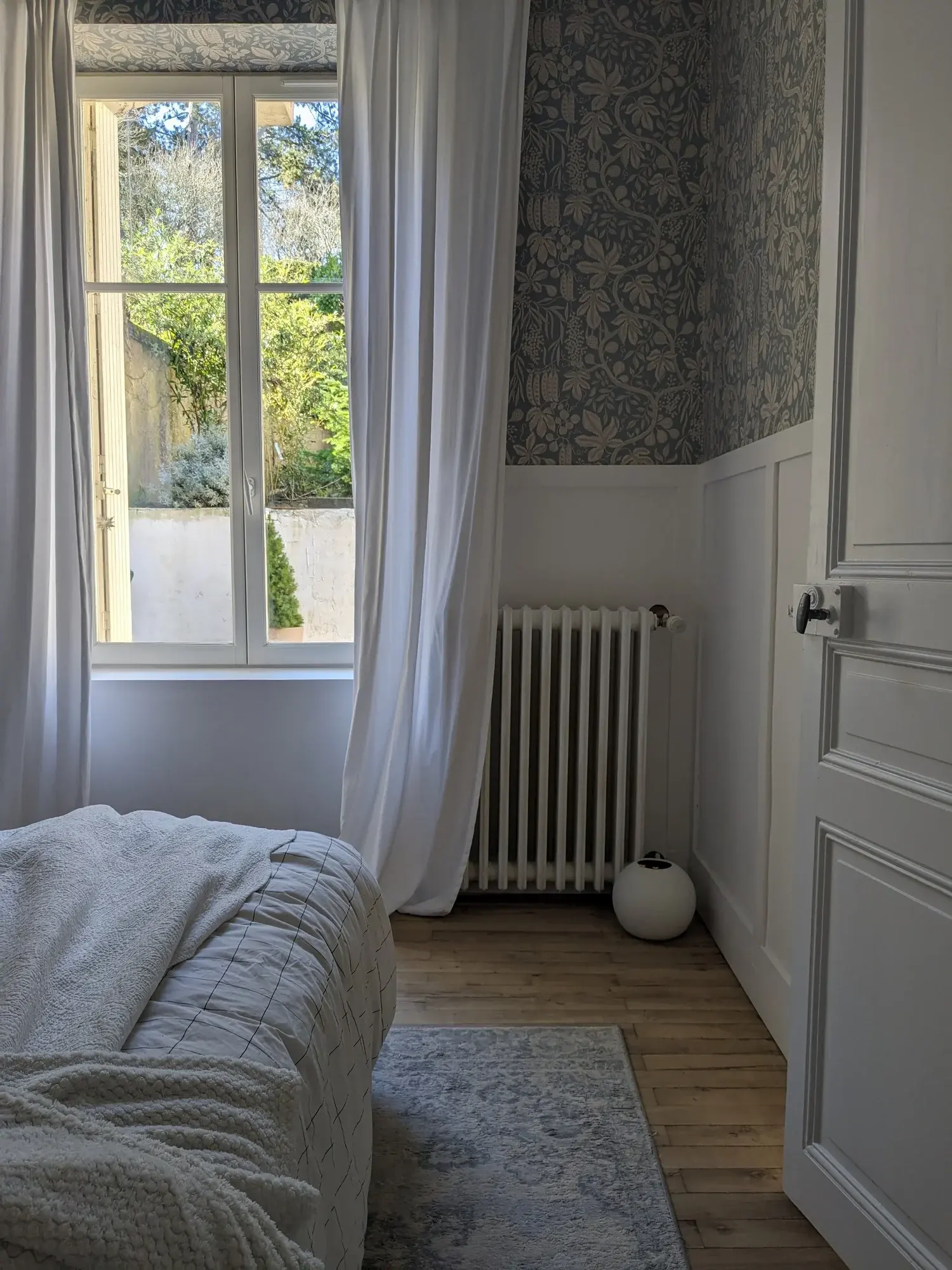 Fenêtre ouverte sur le jardin et radiateur en fonte